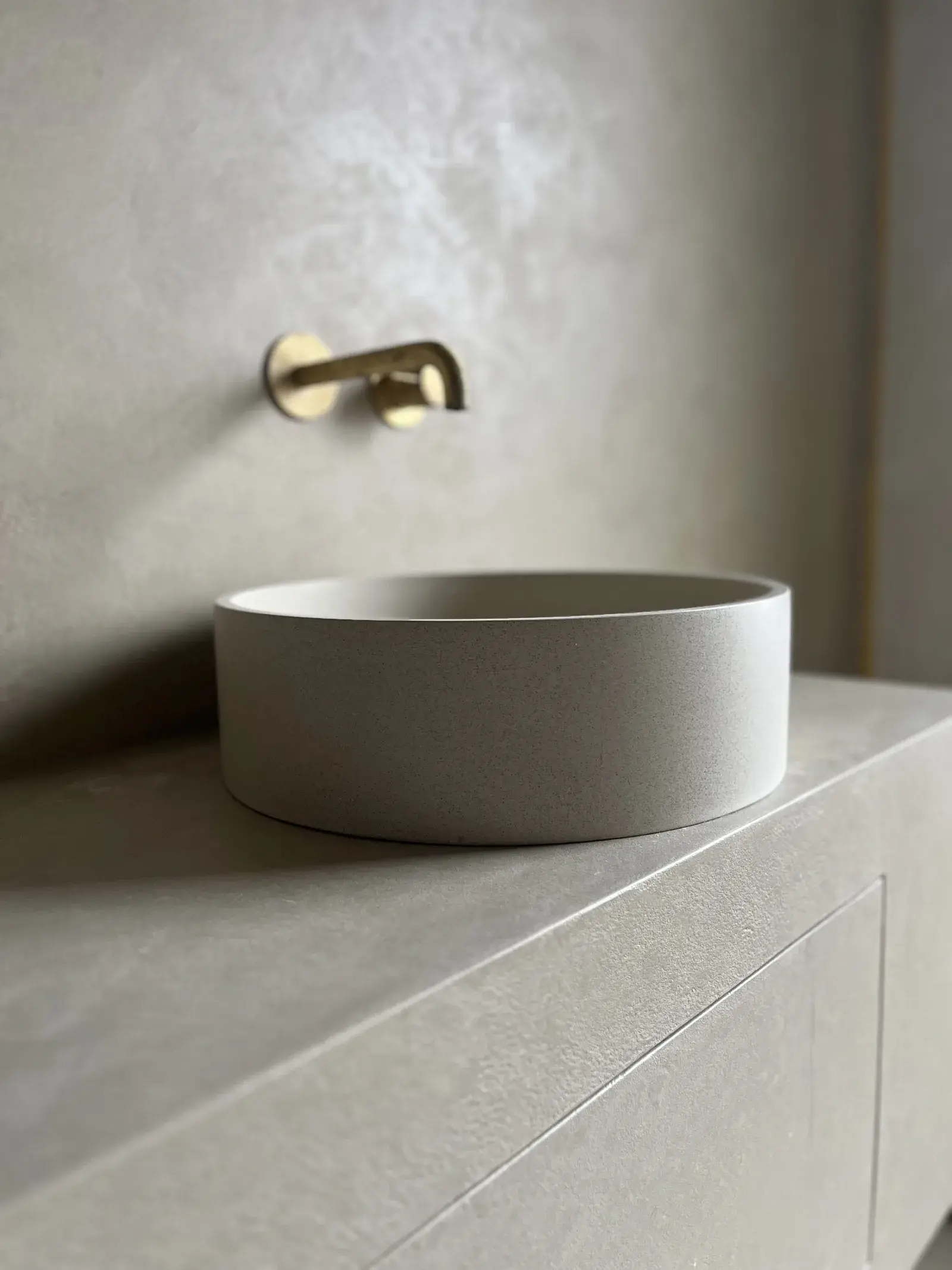 Ronde waskom op microcement meubel met messing muurkraan in badkamer Rotterdam